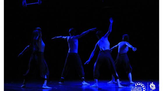 Jóvenes bajo luz azul realizando una representación de danza contemporánea 
