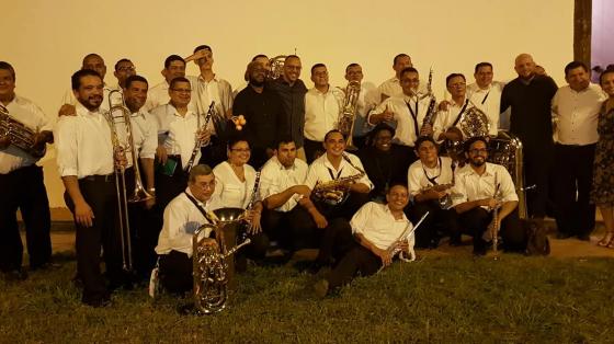 Músicos de la Banda de Concierto de Guanacaste posando junto a sus instrumentos en las afueras de la sede. Noche con iluminación cálida.