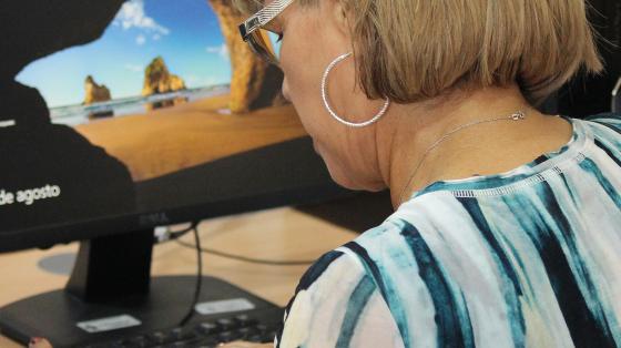 Señora de cabello corto rubio, frente a una computadora 