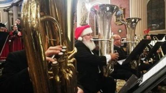 Banda de Conciertos de San José Músico de la Banda de Conciertos de San José con gorrito navideño junto al ensamble