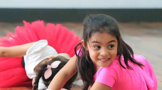 Niñas vestidas de rosado, acostadas en el suelo en clase de ballet