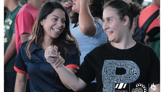 Dos jóvenes muy sonrientes bailando tomadas de las manos