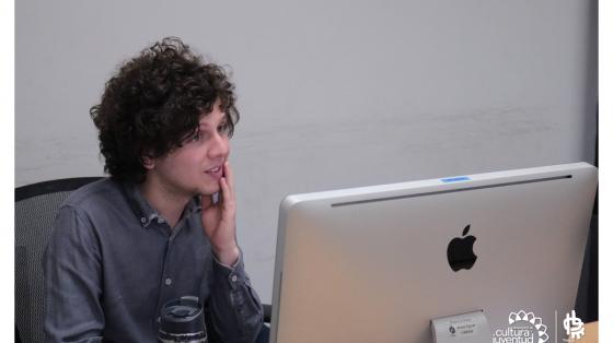 Taller Uso de las plataformas Teams y Google Class Room para docentes Joven con la mano en la cara frente a una computadora prestando atención