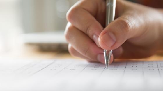 Mano escribiendo en un papel con un bolígrafo