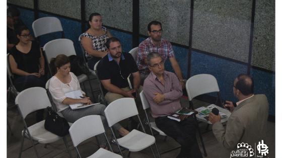 Grupo de personas prestando atención a una persona que explica un tema