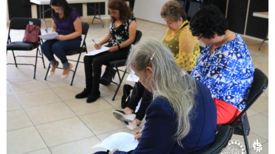 Grupo de personas en un semi-circulo escribiendo sus ideas en un papel