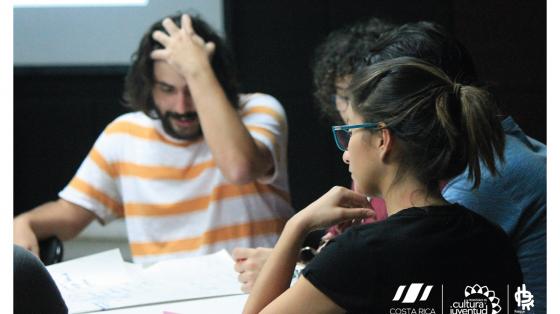 Tres personas en una mesa recibiendo una capacitación.