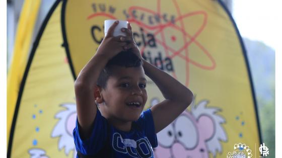 Niño celebrando el día del niño, y está jugando mientras se pone un vaso en la cabeza