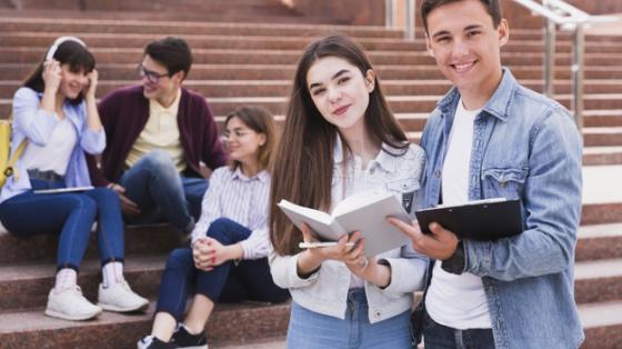 Estudiantes de pie con libros abiertos mirando hacia la 