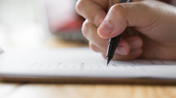 Taller literario Mano escribiendo con un bolígrafo sobre papel