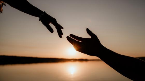 manos de pareja a contra luz de un atardecer