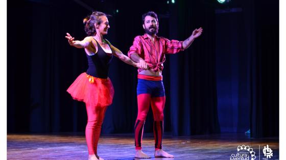 Dos actores con vestuarios muy llamativos presentándose en una tarima