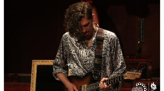 Joven guitarrista presentándose en un teatro 