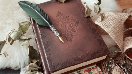 Pluma sobre un libro antiguo cubierto de pétalos de flores secas