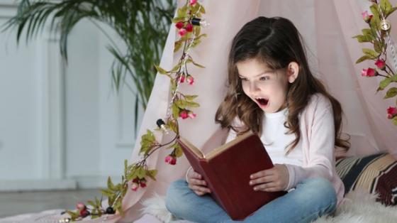 Niña leyendo sentada en el suelo y atrás una linda decoración