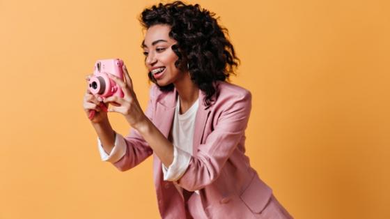 Mujeres en la fotografía por Sussy Vargas y Mariechen Wust Mujer sonriente con chaqueta rosa, tomando una fotografía