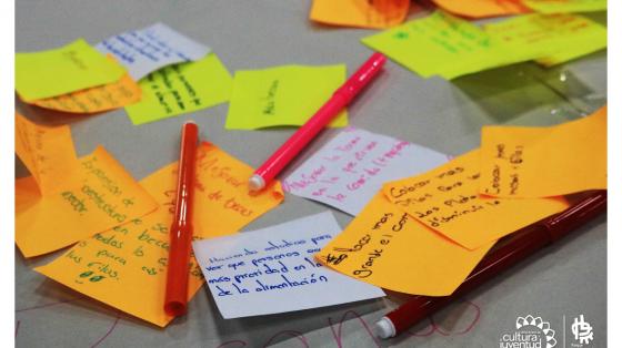 Charla: Administrar mi salario Muchos papeles de colores y lapiceros con apuntes