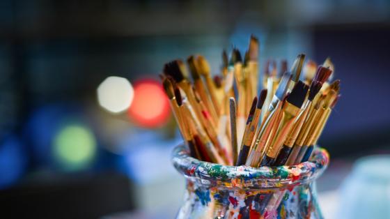 Artístico Frasco de vidrio manchado de pintura con pinceles.