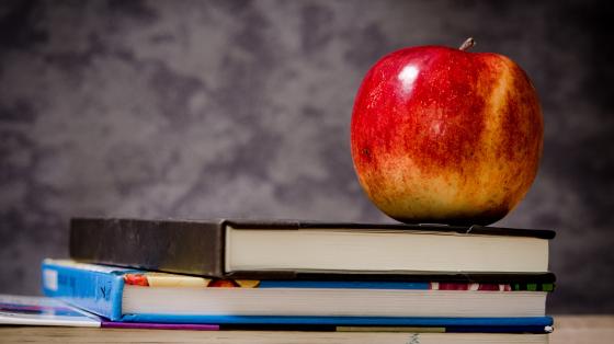 Una manzana sobre tres libros apilados. 
