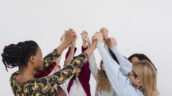 Grupo de mujeres tomadas de la mano en círculo. 