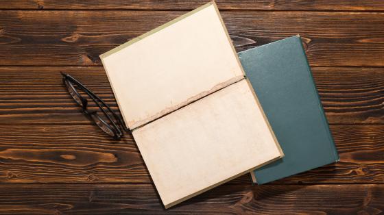 Presentación de la antología "Con letra de médico" de la Asociación de la Asociación Costarricense de Médicos Jubilados Libros y anteojos en mesa de madera con vista superior.