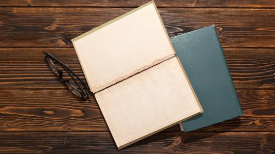 Libros y anteojos en mesa de madera con vista superior.