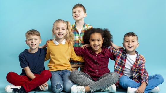 Aprendiendo a tocar y bailar Calypso: actividad para niñas y niños Fotografía con fondo celeste. Se presentan tres niños y dos niñas.