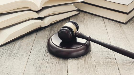 Mazo de justicia Fotografía de un mazo o mallete de justicia, a su lado se encuentran tres libros abiertos.