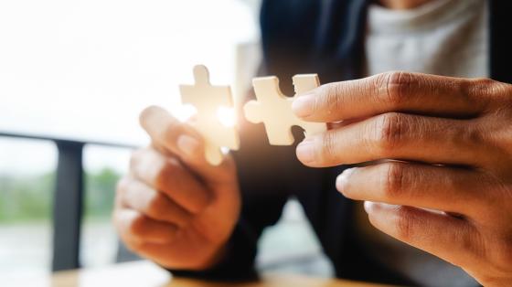 Cómo ser un emprendedor/ra psicológicamente asertiva Persona uniendo dos piezas de rompecabezas.