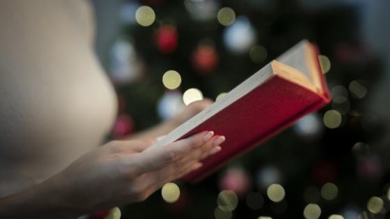 Cuenta cuentos navideños Persona sosteniendo un libro abierto. Fondo navideño.