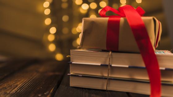 Concierto de navidad con el Coro Lírico de Heredia Fondo con luces. Sobre una mesa de madera, dos libros apilados y un regalo.