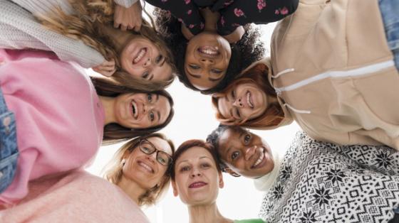 Taller de Inglés para Mujeres Emprendedoras Grupo de mujeres formando un círculo y mirando abajo.