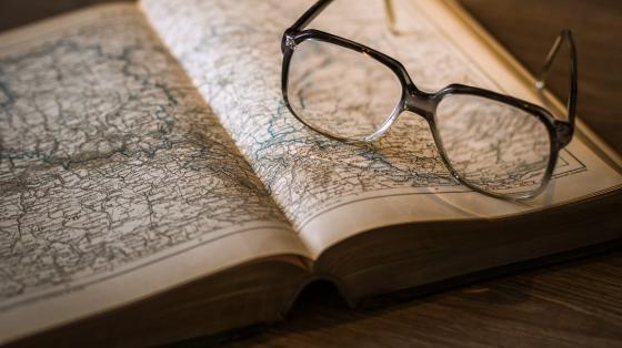 La Batalla de Santa Rosa: Trascendencia histórica y causas geopolíticas Imagen de un libro abierto a la mitad con ilustraciones de mapas y unos lentes abiertos sobre el libro.