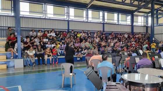 Foto de los músicos en un gimnasio ofreciendo un concierto a público infantil