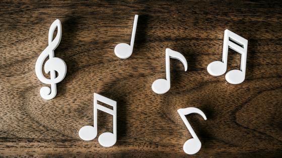 Conversatorio “Música y baile popular” Sobre una mesa de madera, 6 piezas de madera blancas en forma de notas musicales.
