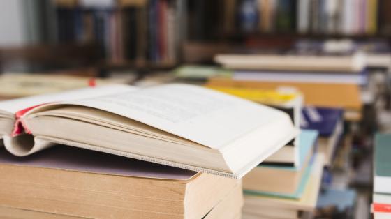 Pila de libros en una librería. En primer plano un libro abierto.