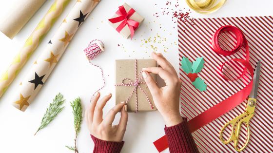 Elaboración de envoltorios navideños Manos de una persona envolviendo un regalo.