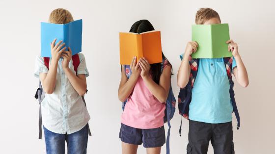 Grupo de niños con un libro en su cara.