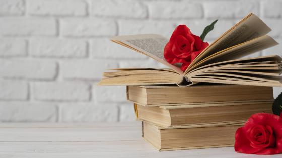 Celebre el Día Nacional de la Poesía Fondo blanco. Composición de libros con rosas.