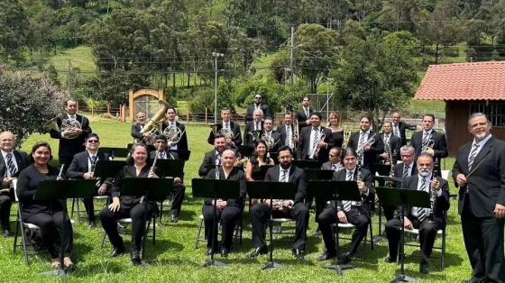 músicos de la Banda de Cartago en un espacio al aire libre con naturaleza de fondo