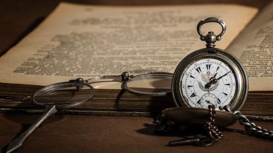 Un libro abierto con unos lentes para leer y un reloj de bolsillo antiguo. Un paseo por la historia de Costa Rica