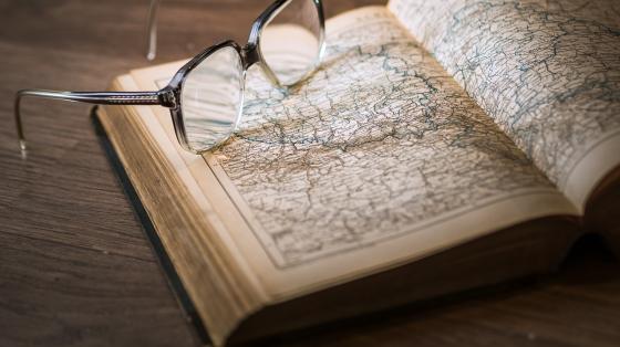 Un libro abierto y unos lentes sobre el libro