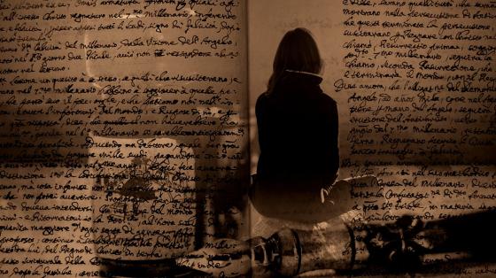 Exposición A 200 años de la Abolición de la Esclavitud en Centroamérica Unas páginas de un libro abiertas traslúcidas una persona sentada de espaldas y otros objetos alrededor