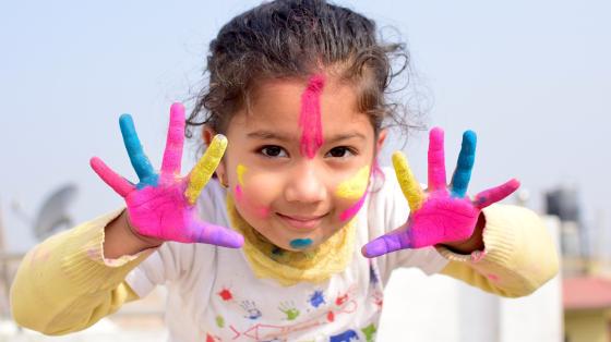 Taller para niños y niñas: Aprendiendo a hacer máscaras Una niña con la cara y manos pintadas con pintura de colores