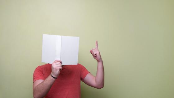 Una persona leyendo un libro abierto frente a la cara