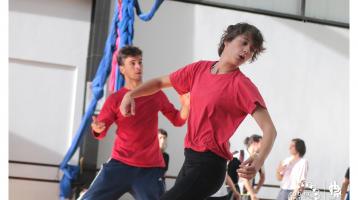 Dos jóvenes con camisa roja realizando movimientos con los brazos en clases de teatro