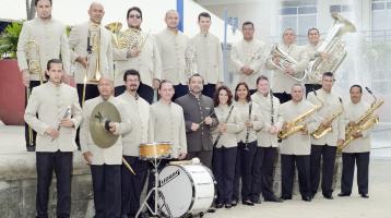 En la foto posan los músicos de la Banda de Conciertos de Puntarenas vestidos con sus guerreras color beige. Lucen muy elegantes y sonrientes junto a sus instrumentos.