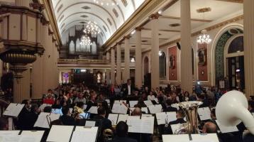 Músicos de la Banda de Conciertos de San José tocando en una iglesia con mucho público asistente
