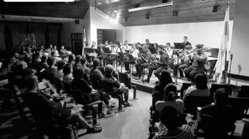 Foto en que se aprecia al público disfrutando de la música con la Banda de Conciertos de Limón. La imagen resalta con perspectiva la afluencia del público y se observa al ensamble ubicados armoniosamente en el espacio.