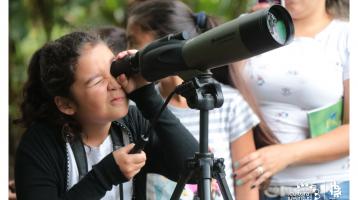 Niña mirando aves y la naturaleza con telescopio